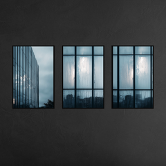 Three panel urban architecture wall art with slim black metal frames mounted on charcoal textured wall, featuring reflective skyscraper and rain soaked windows