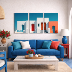 Three panel Mediterranean facade wall art with turquoise sky and bold red doors installed above blue sofa in coastal style living room setting