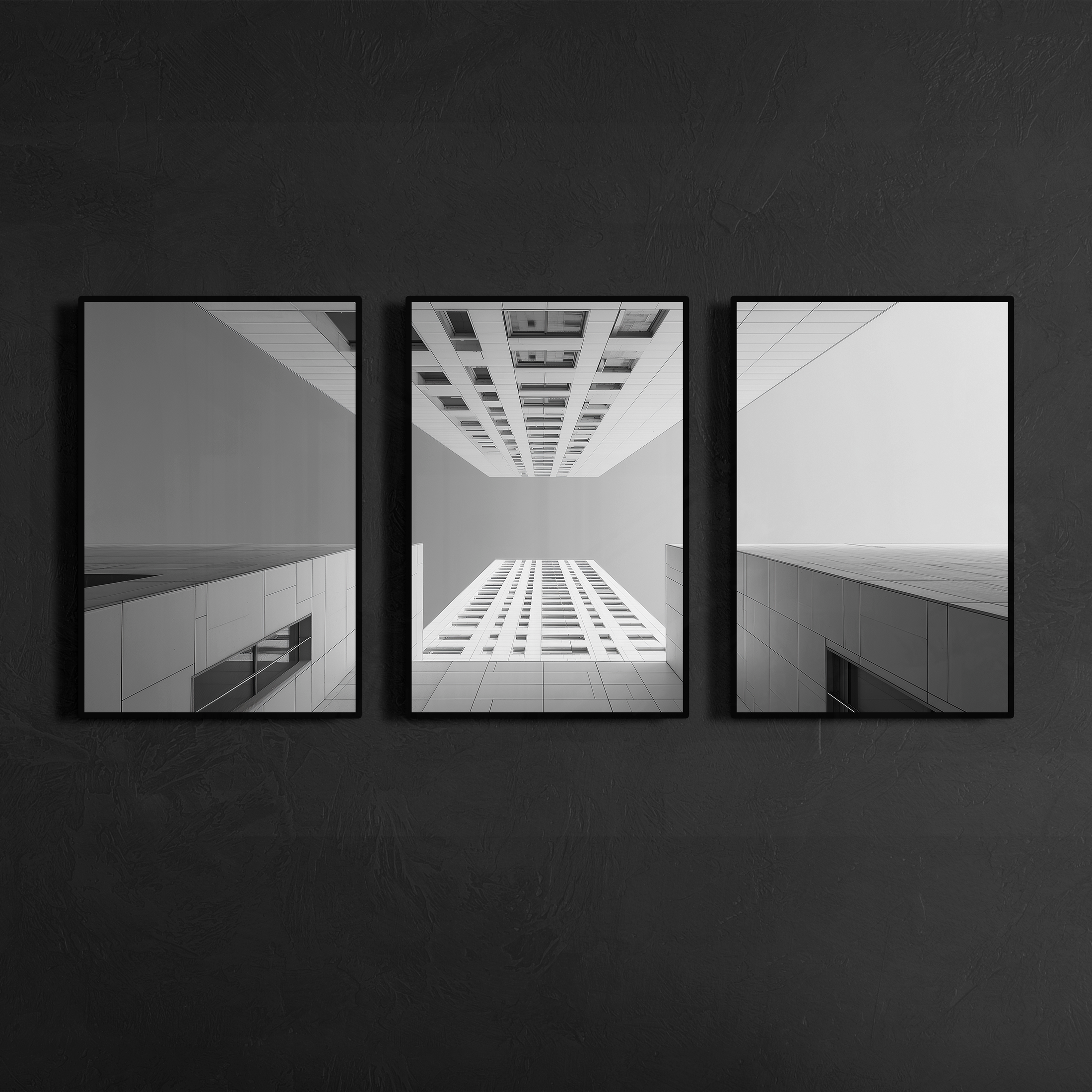 Three panel black and white skyscraper wall art with slim black metal frames mounted on charcoal textured wall, modern luxury interior statement piece