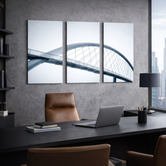 Clean architectural bridge triptych wall art above dark desk in contemporary office interior, minimalist steel lines and neutral tones printed on premium aluminum