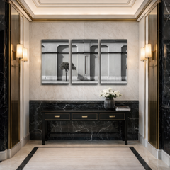 Three panel black and white architectural facade wall art installed in luxury marble hallway with brass wall sconces and black console table