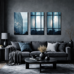 Three panel blue toned architectural wall art featuring reflective glass skyscraper and rain covered windows, displayed above dark grey sofa in modern luxury living room